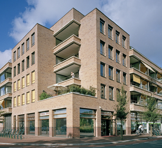 Voorbeeldfoto van een gebouw van vijf verdiepingen waarvan de gevel verspringt. Op de begane grond zit een bedrijfje. Op de hoek van het gebouw ligt de gevel vanaf de tweede verdieping een stuk terug. Het appartement op de eerste verdieping heeft een dakterras. Daarboven hebben de appartementen inpandige balkons.